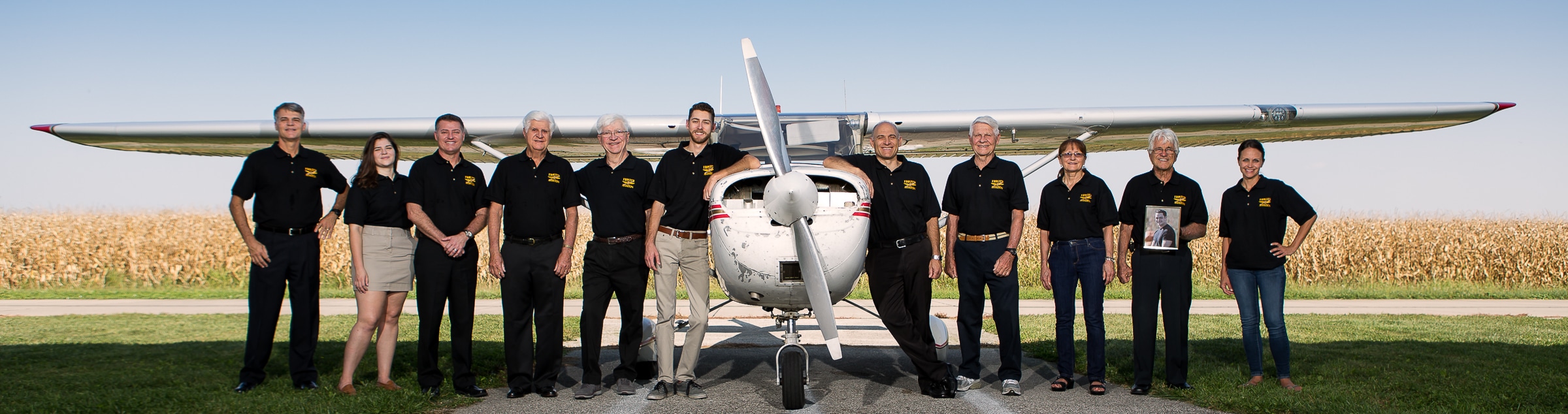 several people stand near a Cessna airplane