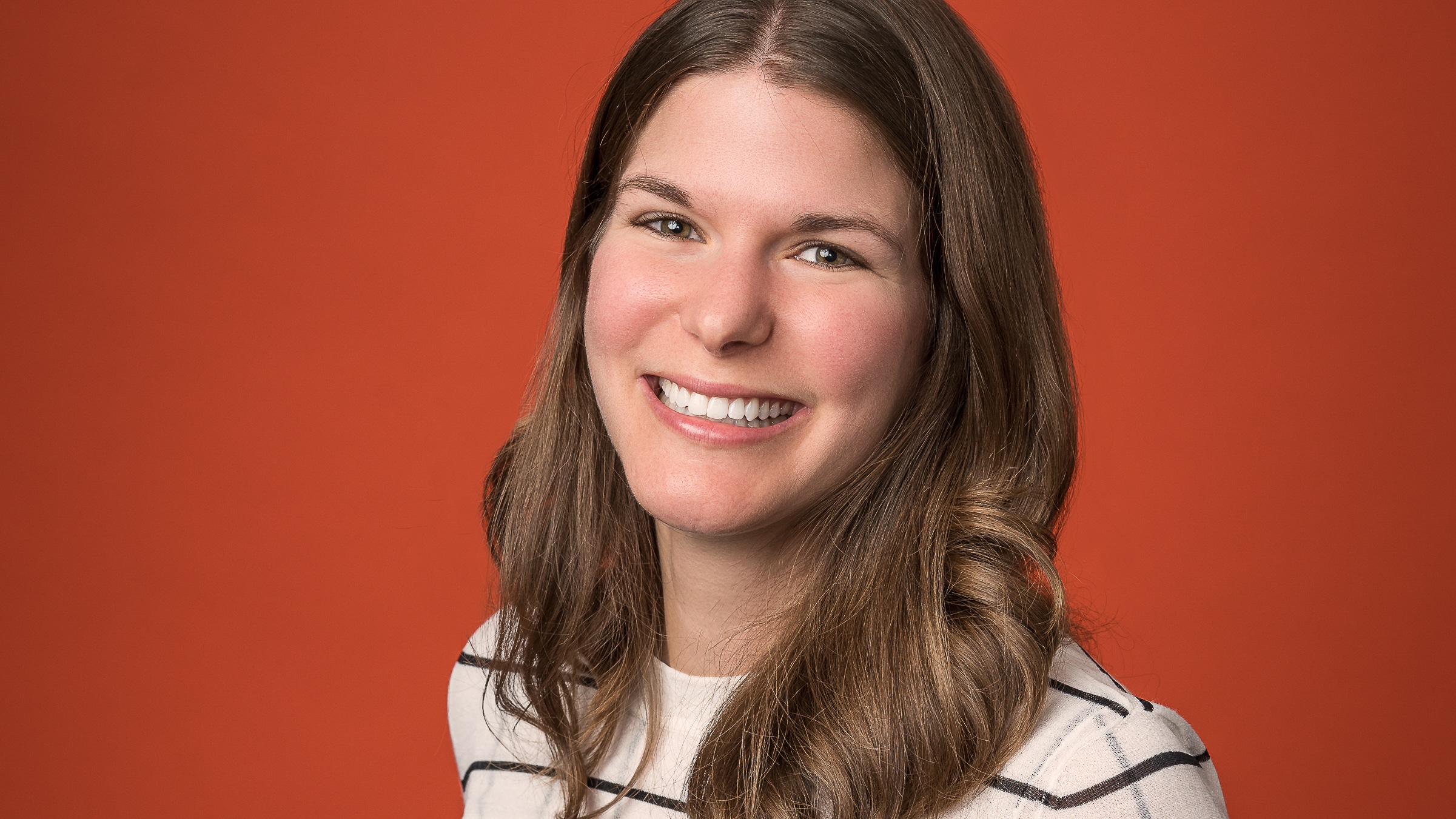 closeup of woman smiling with orange background