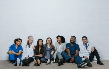 Group of medical personnel A group of doctors, nurses and staff seated against a wall