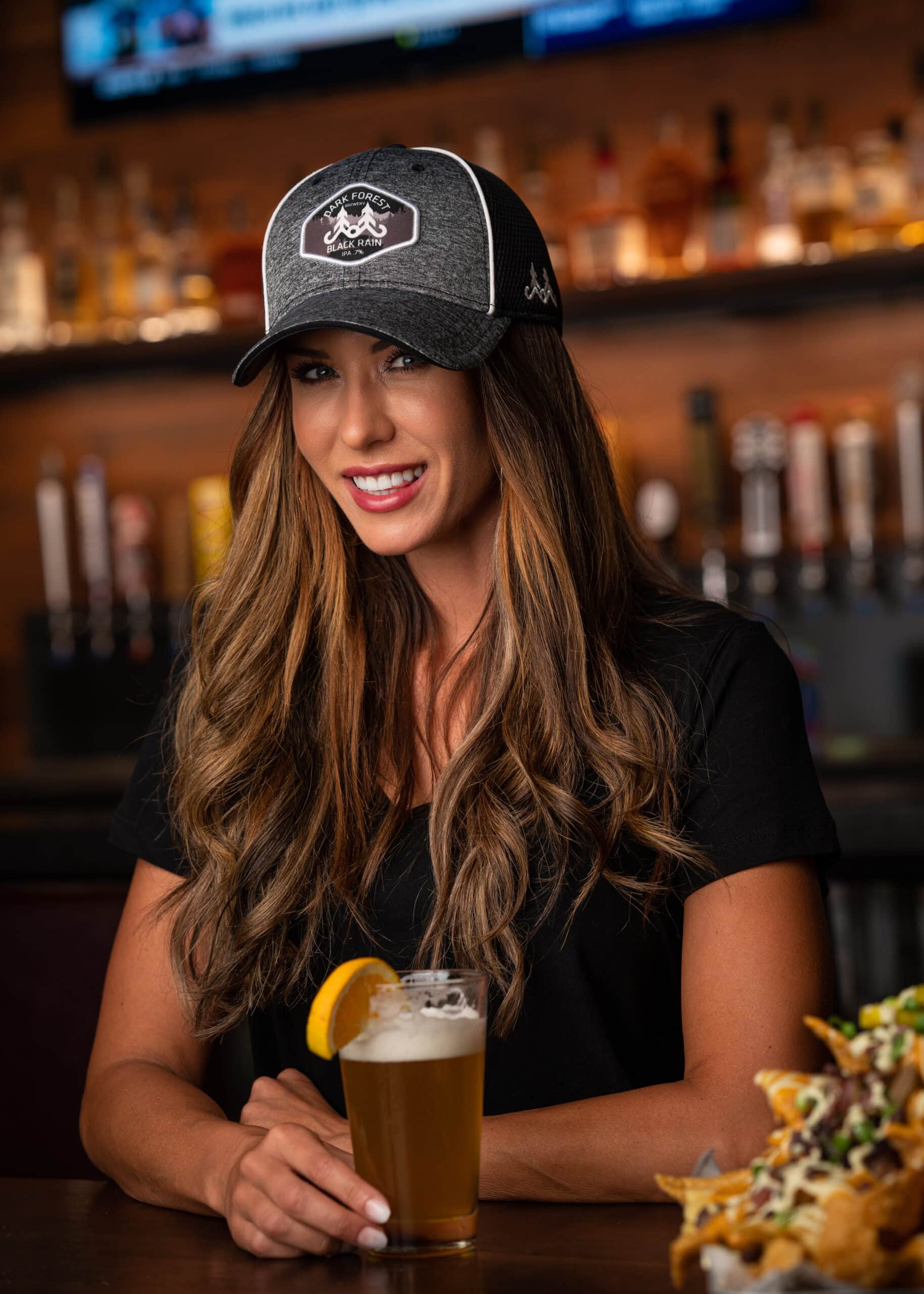 Woman in bar wearing hat Woman in bar with beer, nachos and hat