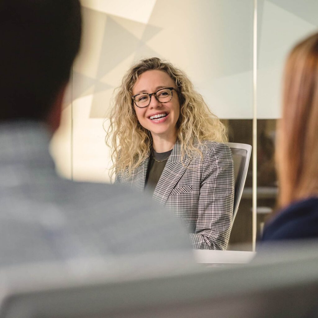 Meeting photo of woman smiling at colleagues woman in office smiling in meeting