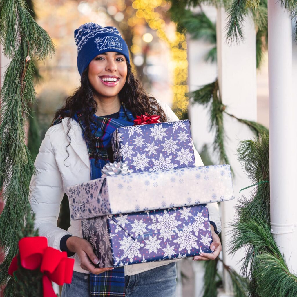 st louis catalog photography Catalog photograph of woman in blue knit stocking cap, winter holiday decor, carrying wrapped gifts