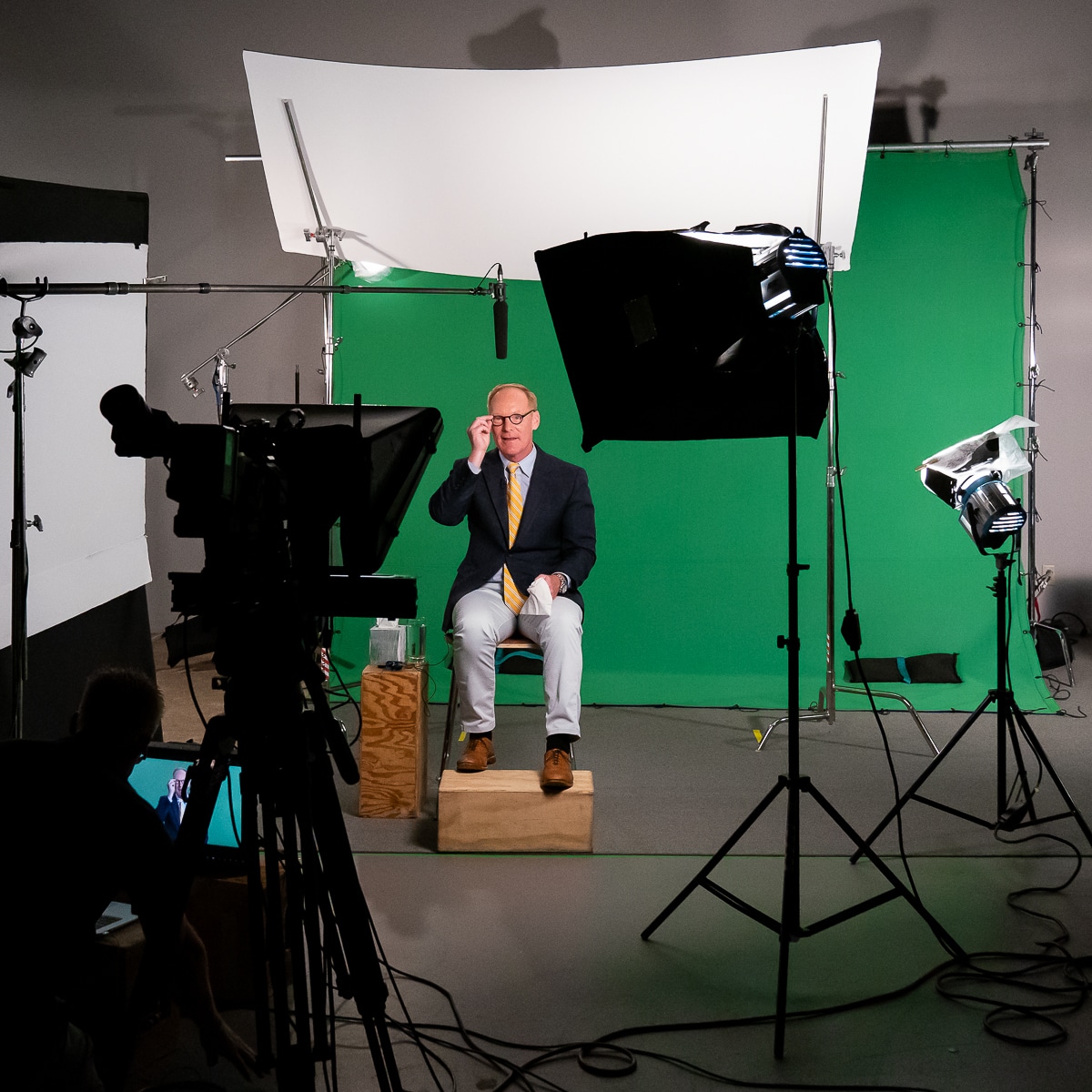man seated on video production set in front of a green screen