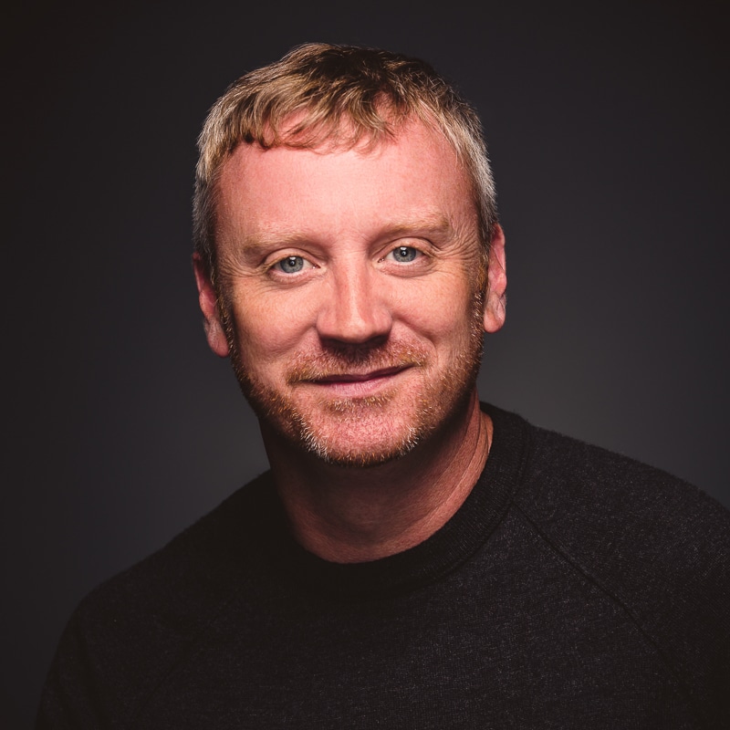 Dan Duffy headshot man in black in studio