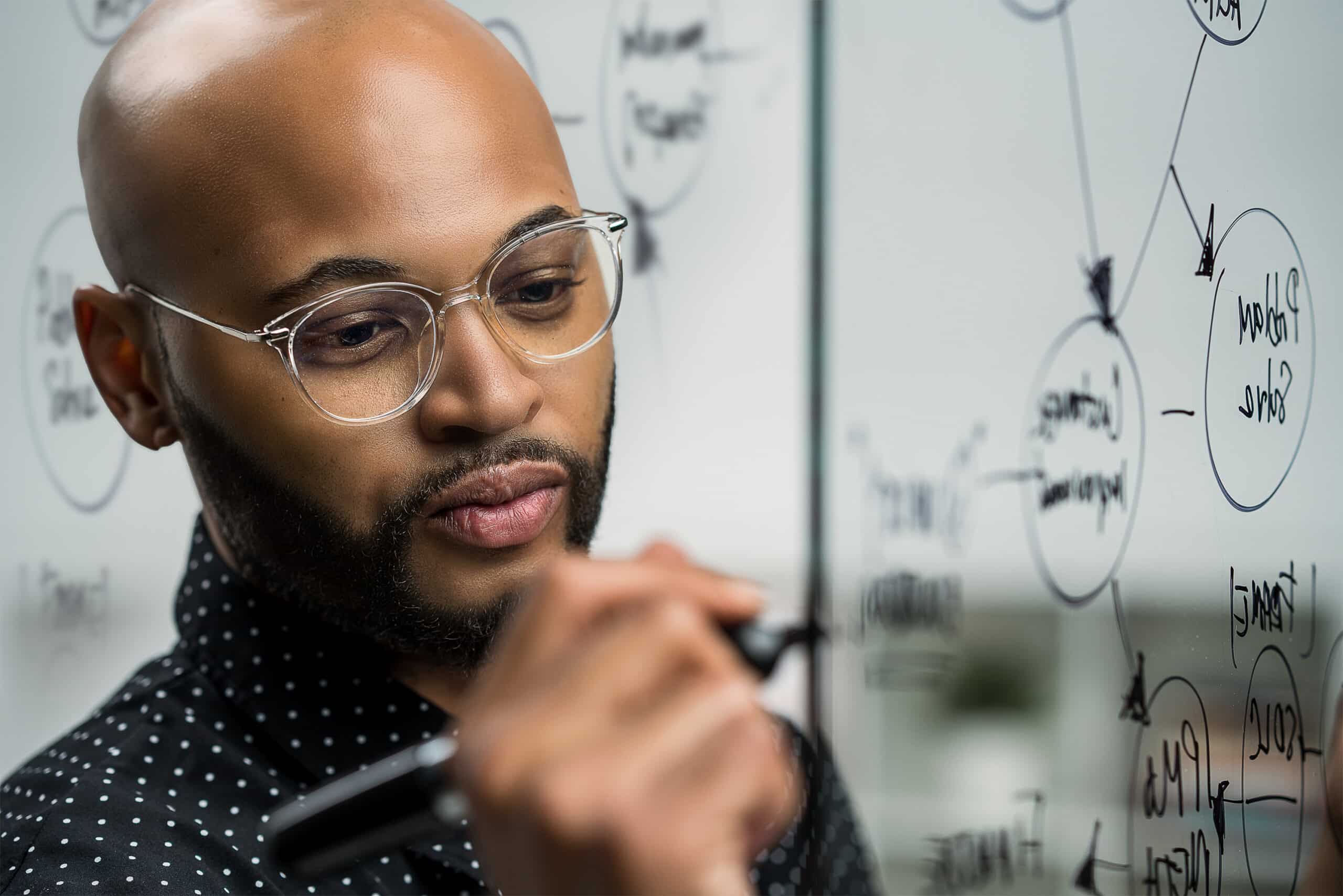 data scientist writing equation man with glasses writing equation