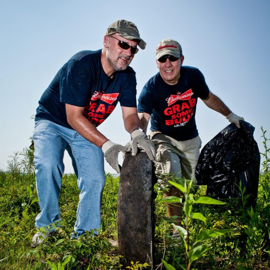 Two men carry debris and refuse outdoors
